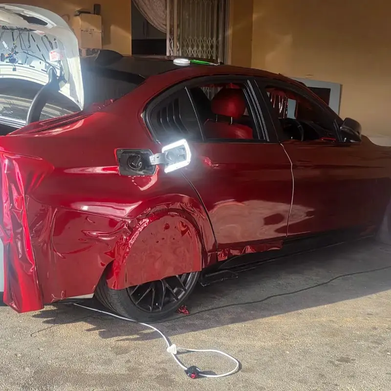 Detailed vehicle wrapping featuring precision application of burgundy vinyl around rear doors, wheel arches and body contours.