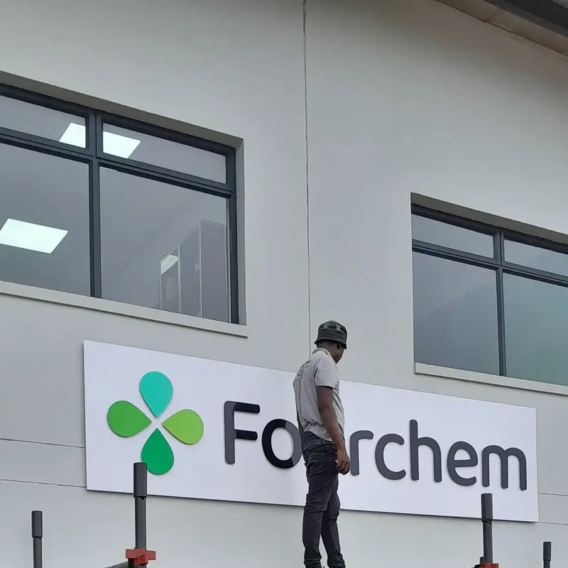 Professional high-level exterior signage installation using scaffolding to safely position and mount commercial building graphics.