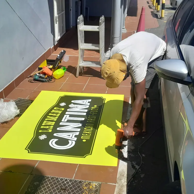 Preparation of large-format printed promotional vinyl before professional installation, demonstrating careful material handling and positioning.