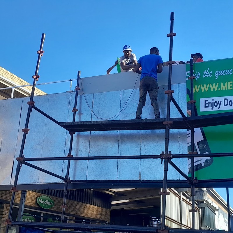 Professional high-level commercial signage installation involving scaffolding, sign positioning and secure exterior mounting.